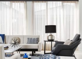 Modern living room interior with sofas, black armchair, and a patterned rug.